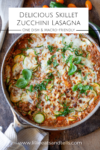 A skillet filled with Skillet Zucchini Lasagna, topped with melted cheese and fresh basil, sits invitingly on a wooden surface. Text overlay reads: Delicious Skillet Zucchini Lasagna, One Dish & Macro-Friendly.