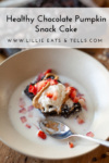 A chocolate pumpkin snack cake topped with ice cream, peanut butter, and chopped strawberries sits in a bowl of milk, with a spoon beside it. Text above reads Healthy Chocolate Pumpkin Snack Cake—a delicious twist on your favorite chocolate pumpkin snack cake.