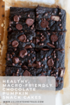 A pan of sliced chocolate pumpkin snack cakes topped with chocolate chips, viewed from above, on parchment paper. Text overlay reads: Healthy, macro-friendly chocolate pumpkin snack cake.
