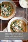 Two bowls of Macro-Friendly Beef and Kale Soup sit on a wooden table, topped with fresh herbs, with a bowl of grated cheese nearby. Text overlay reads: Macro-Friendly Beef and Kale Soup www.lillieeatsandtells.com.