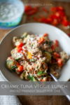 A bowl of creamy tuna and mixed vegetables on rice, topped with chopped red peppers, with a fork beside it—perfect for a Creamy Tuna Veggie Lunch Skillet for One. In the blurred background, a tub of sauce and more chopped veggies can be seen.