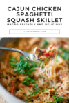 A fork lifting a bite of Cajun Chicken Spaghetti Squash Skillet, garnished with fresh herbs, from a pan. Text above describes this Cajun Chicken Spaghetti Squash Skillet as macro-friendly and delicious.