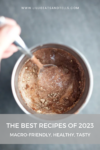A spoon stirs a rich chocolate mixture in a metal cup, viewed from above. Text at the bottom reads: The Best 5 Most Popular Macro-friendly Recipes from 2023. Healthy, tasty, and perfect for your goals. Website URL appears at the top.