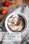 A bowl of chocolate oatmeal topped with banana slices, whipped cream, peanut butter, and cocoa nibs sits on a wooden table with strawberries nearby. This cozy treat is perfect for date night at home recipes. Text reads Date Night At Home Recipes.