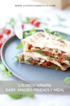 Two triangular crunch wraps filled with chicken, veggies, and greens sit on a dark plate. The background is blurred with hints of cherry tomatoes and greens. Text overlay reads: Macro-friendly Crunch Wraps: Easy, Nutritious Meal.