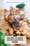 Grilled chicken breasts rest on a wooden board, garnished with fresh herbs and a spicy jalapeño, overlaid with the text: 5 Recipes to Make Macro-Counting Easier—perfect for anyone looking to simplify their meal planning while hitting their nutritional goals.