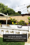 Modern outdoor kitchen with a grill, sink, six white bar stools, string lights, lush plants, and a wooden fence. Text overlay reads: Why I Love My Outdoor Kitchen.