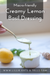 A hand holds a spoon drizzling creamy Lemon-Basil Dressing into a small white ramekin, with fresh lemons and basil in the background. Text on image: Macro-friendly Creamy Lemon Basil Dressing.