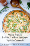 A casserole dish filled with Buffalo Chicken Spaghetti Squash Casserole, topped with herbs and cheese, sits on a white surface next to a wooden spoon, hot sauce, and fresh parsley. Text reads: Macro-friendly Buffalo Chicken Spaghetti Squash Casserole.