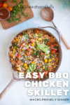A skillet filled with colorful BBQ chicken, butternut squash, corn, tomatoes, onions, and herbs sits on a table next to fresh herbs and a small bowl of sauce. Text on image reads: EASY BBQ CHICKEN AND BUTTERNUT MACRO-FRIENDLY SKILLET DINNER.