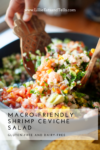 A close-up of Shrimp Ceviche Salad with colorful chopped vegetables in a pan. A wooden spoon is scooping some out. Text overlay reads Macro-Friendly Shrimp Ceviche Salad, Gluten-Free and Dairy-Free.