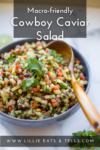 A vibrant bowl of Macro-friendly Cowboy Caviar Salad garnished with fresh cilantro, with a wooden spoon resting inside. Text reads Macro-friendly Cowboy Caviar Salad and www.lillieeatsandtells.com.