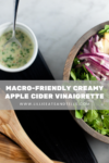 A bowl of fresh salad with radishes and feta sits next to a small cup of Creamy Apple Cider Vinaigrette. Text overlay reads, Macro-friendly creamy apple cider vinaigrette. Wooden salad tongs rest nearby.