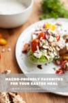 A plate of chicken salad with cherry tomatoes and dressing sits on a wooden table, garnished with herbs. Text overlay reads: Discover macro-friendly favorites for Easter at www.lillieeatsandtells.com.