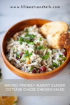 A wooden bowl filled with almost classic cottage cheese chicken salad, garnished with green onions and grapes, sits beside toasted bread slices. A lemon wedge and the website lillieeatsandtells.com appear in the background.
