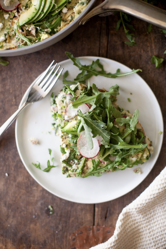 Slice of spring frittata on a white plate with fork.