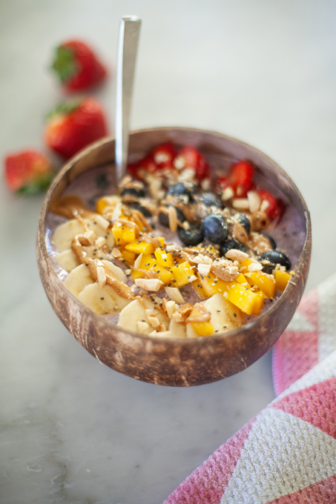 High protein smoothie bowl in bowl with toppings and a spoon.