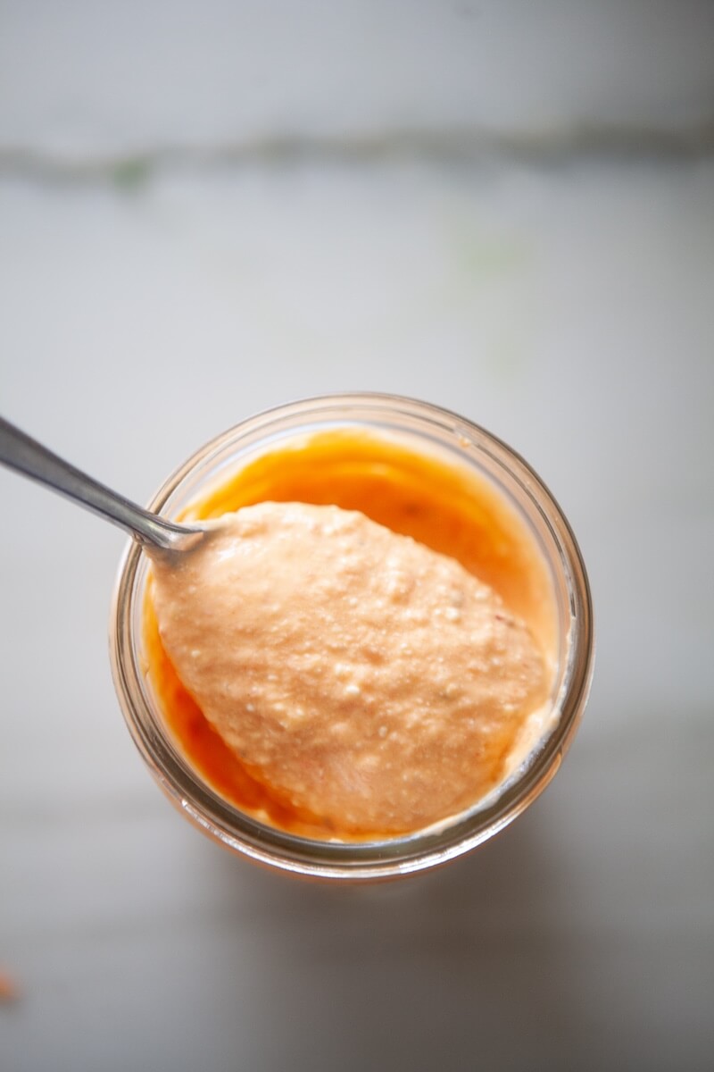 Roasted red pepper feta spread being scooped out of a mason jar.