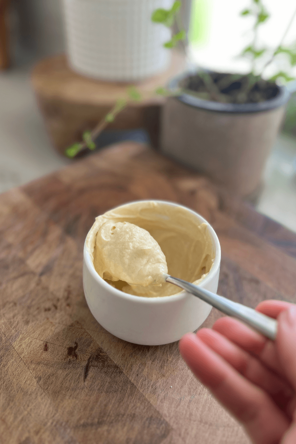 Mustard aioli being scooped out of a white bowl.