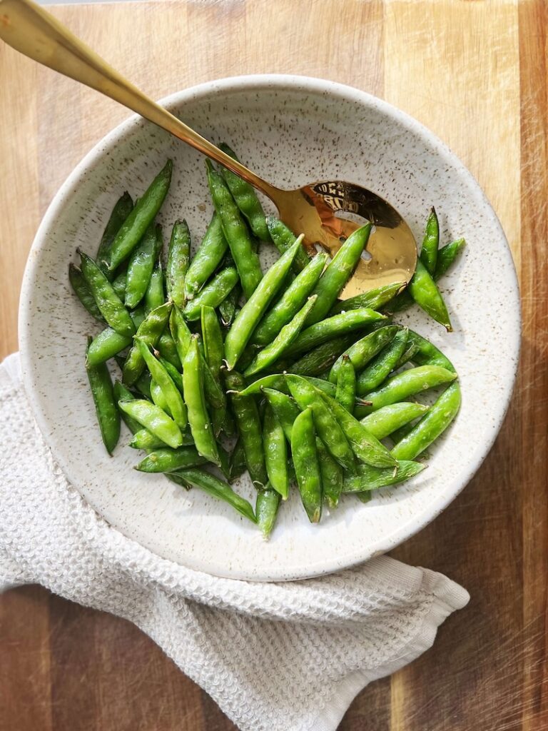Air fried snap peas in a large white bowl.