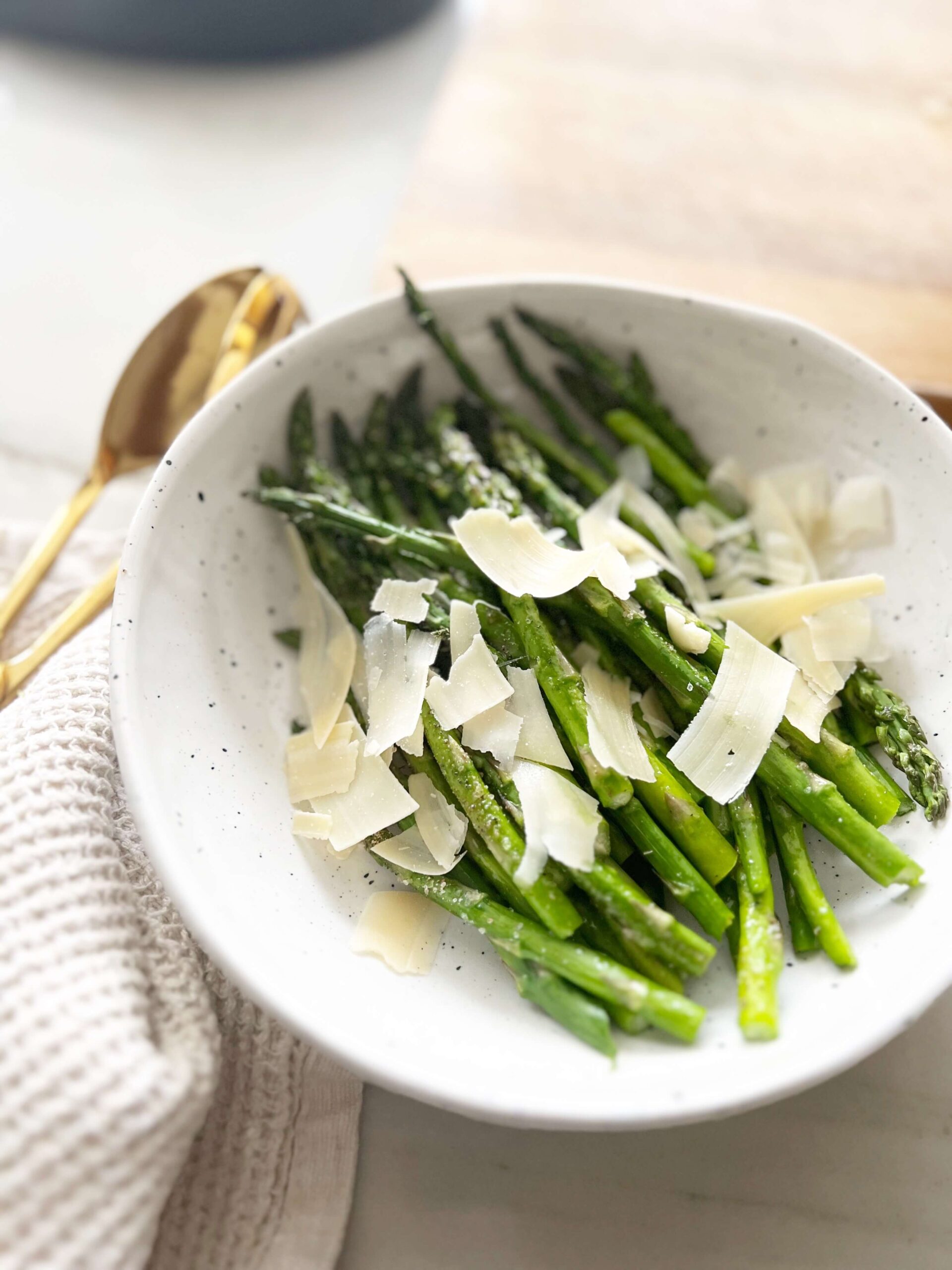 Air fryer asparagus topped with shaved parmesan cheese in a bowl.
