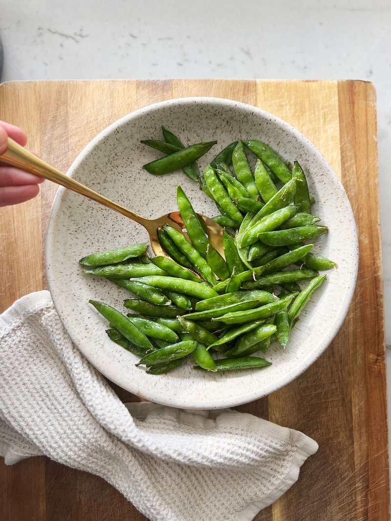 Air fryer snap peas in a large bowl.