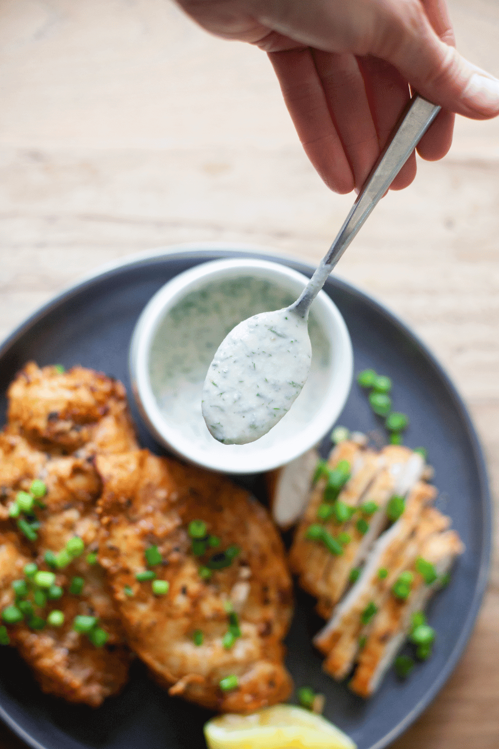 Yogurt herb dressing on a metal spoon.