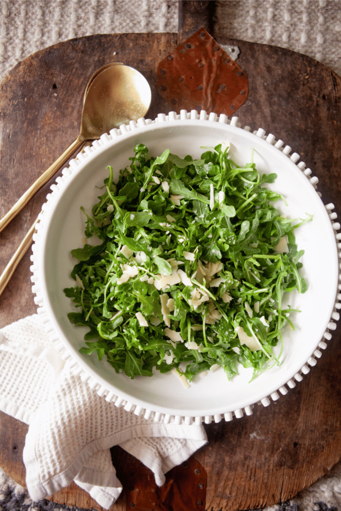 Simple arugula salad served in a white bowl.