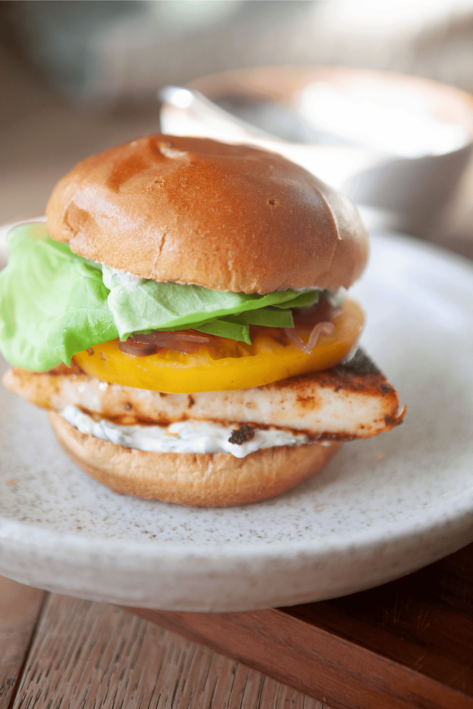 Close up of a blackened fish sandwich on a white plate.