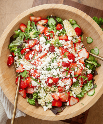 Strawberry Summer Salad in a wooden bowl with spoon on the side.