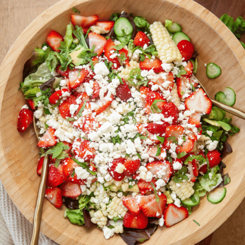 Strawberry Summer Salad in a wooden bowl with spoon on the side.