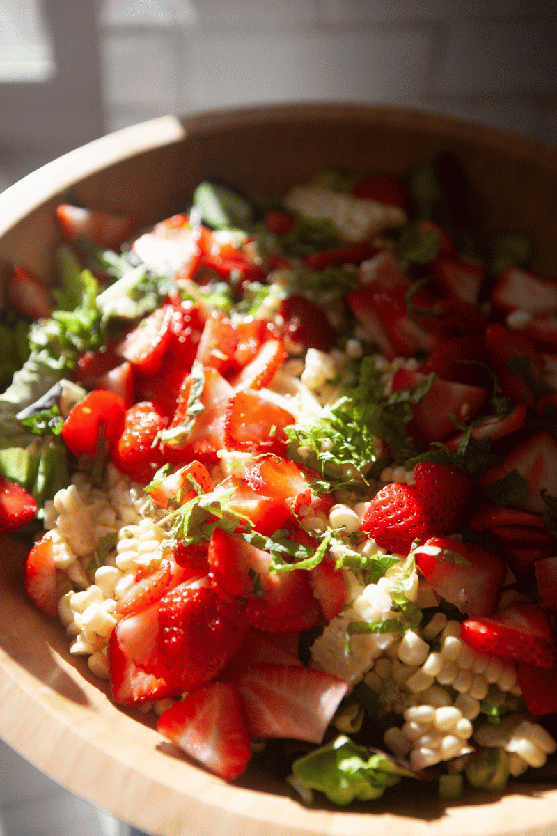 Up close image of strawberry summer salad with half of the bowl covered in shadow.