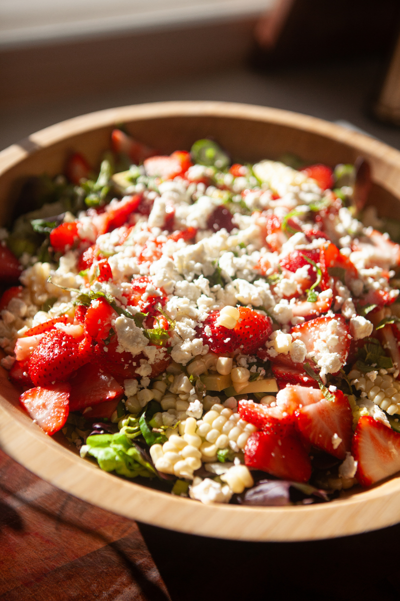 Strawberry salad topped with strawberries, feta cheese, and butter lettuce.