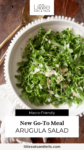 Simple arugula salad with parmesan with text overlay, "Arugula Salad."