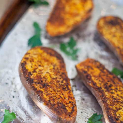 Roasted sweet potato halves on a tinfoil lined pan.