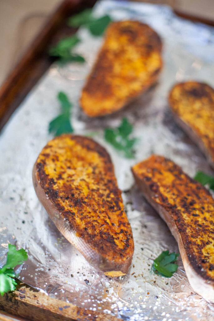 Roasted sweet potato halves on a tinfoil lined pan.