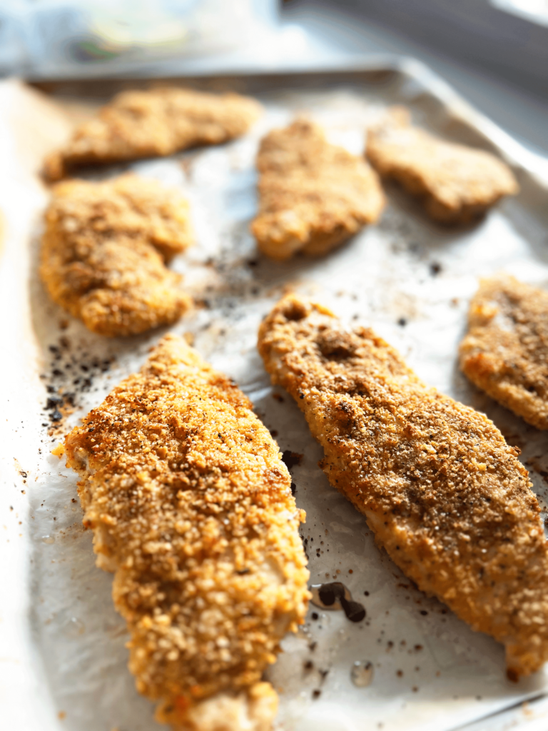 Breaded baked chicken breasts on a baking sheet.