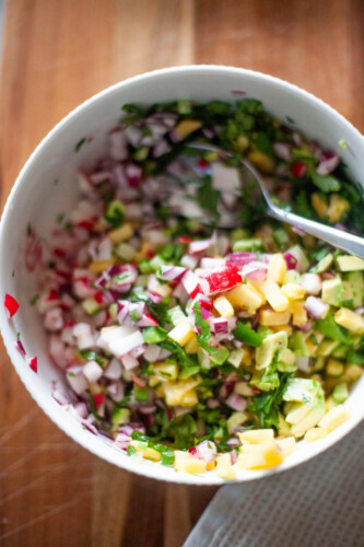 Bowl of pineapple radish salsa with cilantro and red onions.