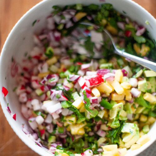 Bowl of pineapple radish salsa with cilantro and red onions.