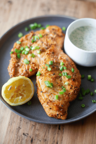 Yogurt marinated air fried chicken with a lemon wedge.