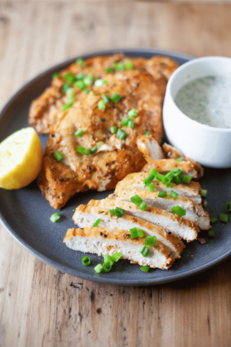 Close up of yogurt marinated air fryer chicken with side of dipping sauce.
