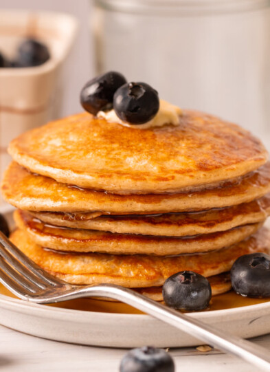 Stack of cottage cheese pancakes on plate with fork.