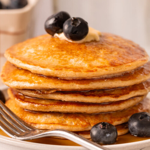 Stack of cottage cheese pancakes on plate with fork.
