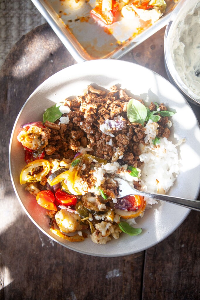 Roasted veggie rice bowl in white bowl and fork.