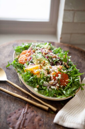 Winter citrus salad on large serving plate with serving utensils.