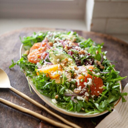 Winter citrus salad on large serving plate with serving utensils.