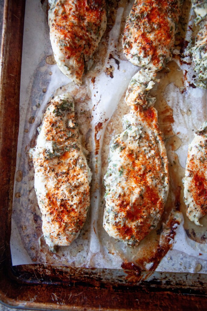 Baked yogurt and herb chicken on baking sheet with parchment paper.