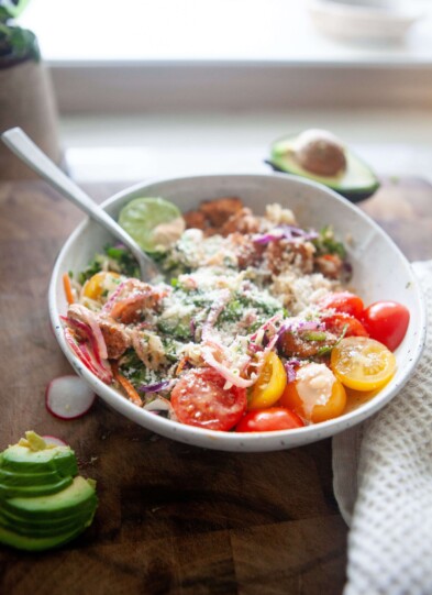 Fish taco bowl sprinkled with cotija cheese in white bowl with fork.