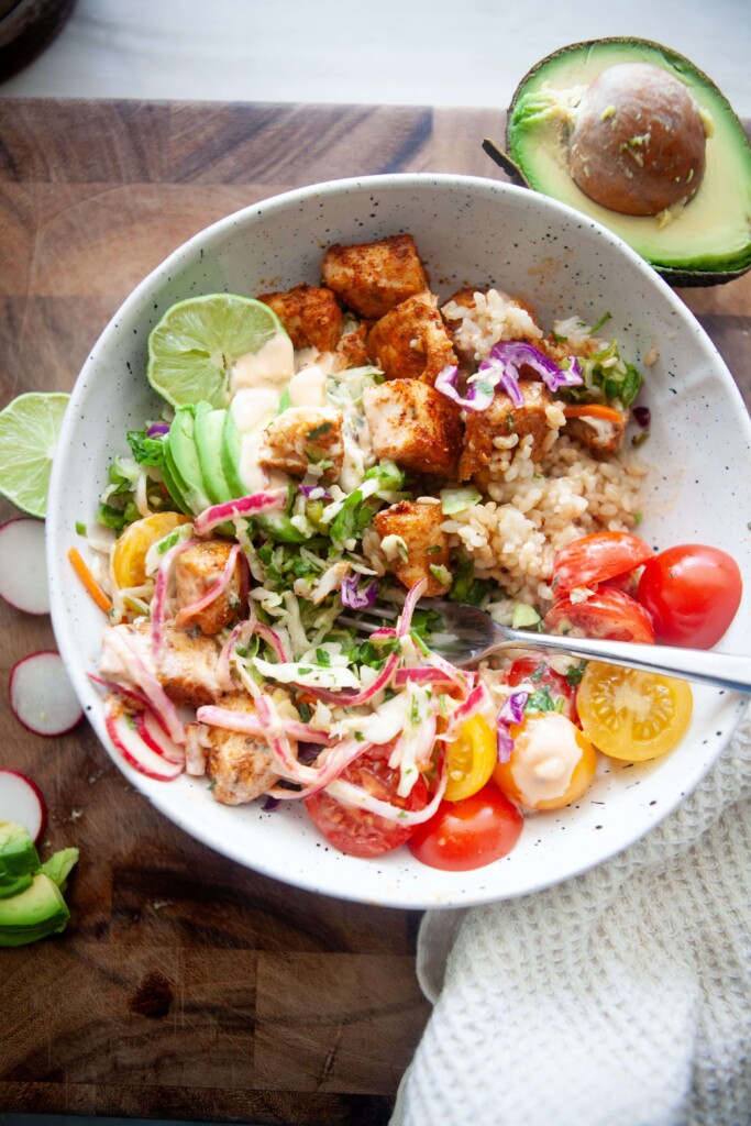 Fish taco bowl in mixed up in white bowl with fork.