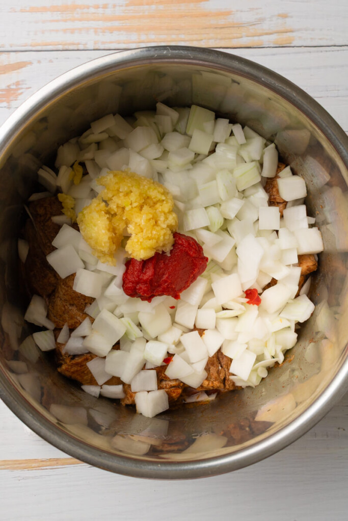 Ingredients added to instant pot for shredded enchilada pork.